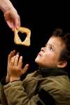 A piece of bread with a heart in the centre being given to a young boy