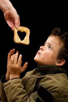 A piece of bread with a heart in the centre being given to a young boy
